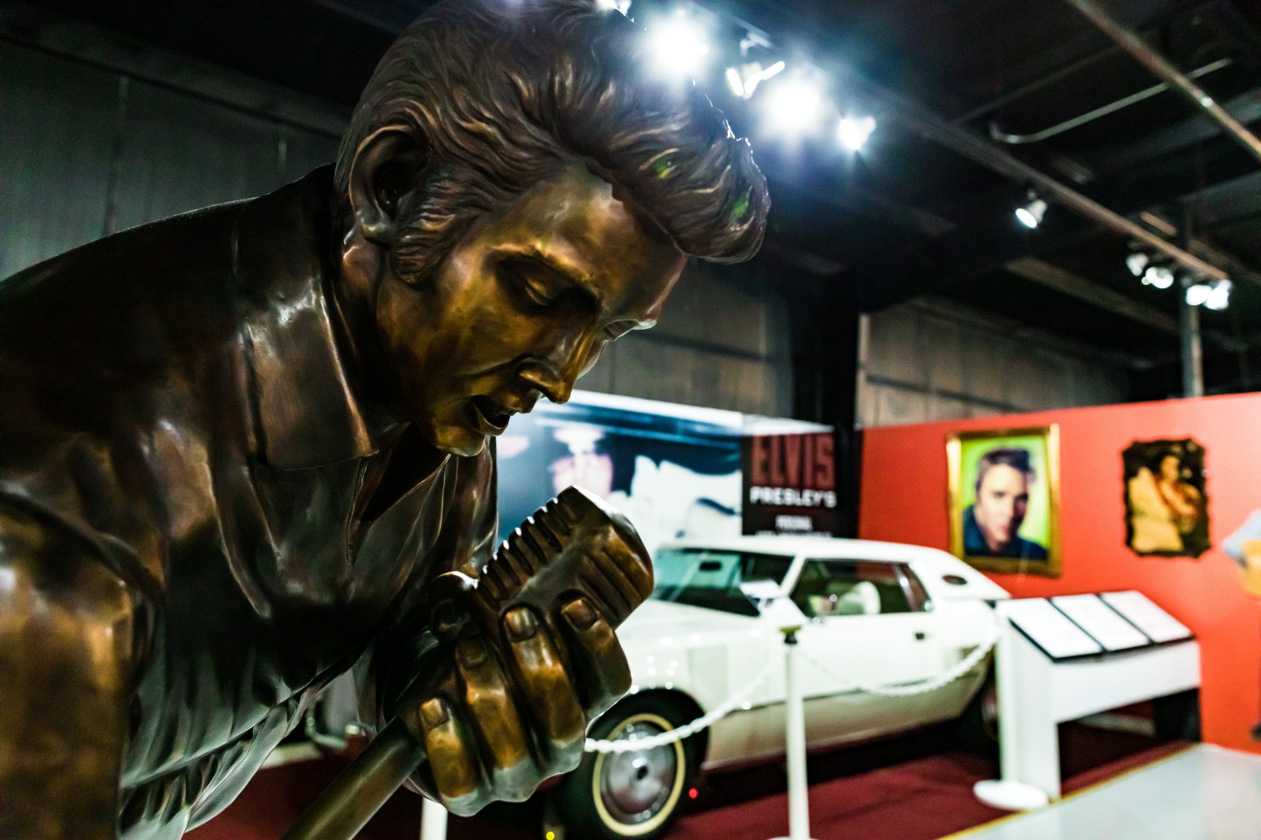 An Elvis Presley statue at the Historic Auto Attractions Museum stands in front of a white Cadillac exhibit.